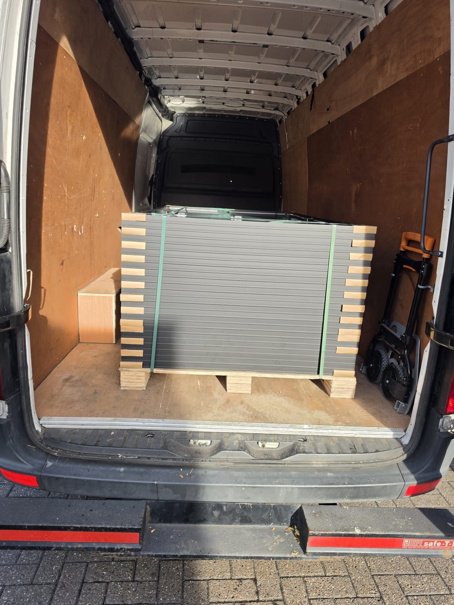 A pallet of grey metal panels strapped inside a long wheelbase van