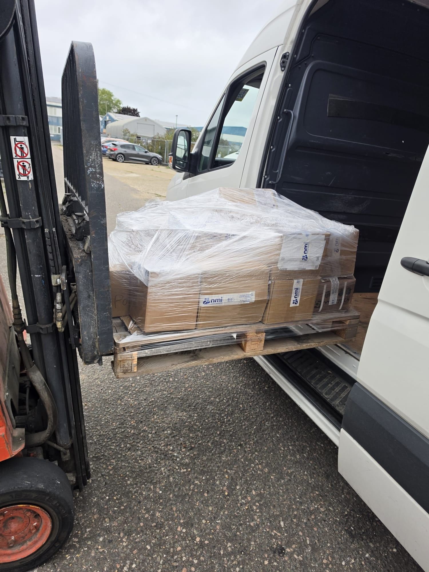 A wrapped pallet of boxes being loaded by forklift into an Encea Transport van